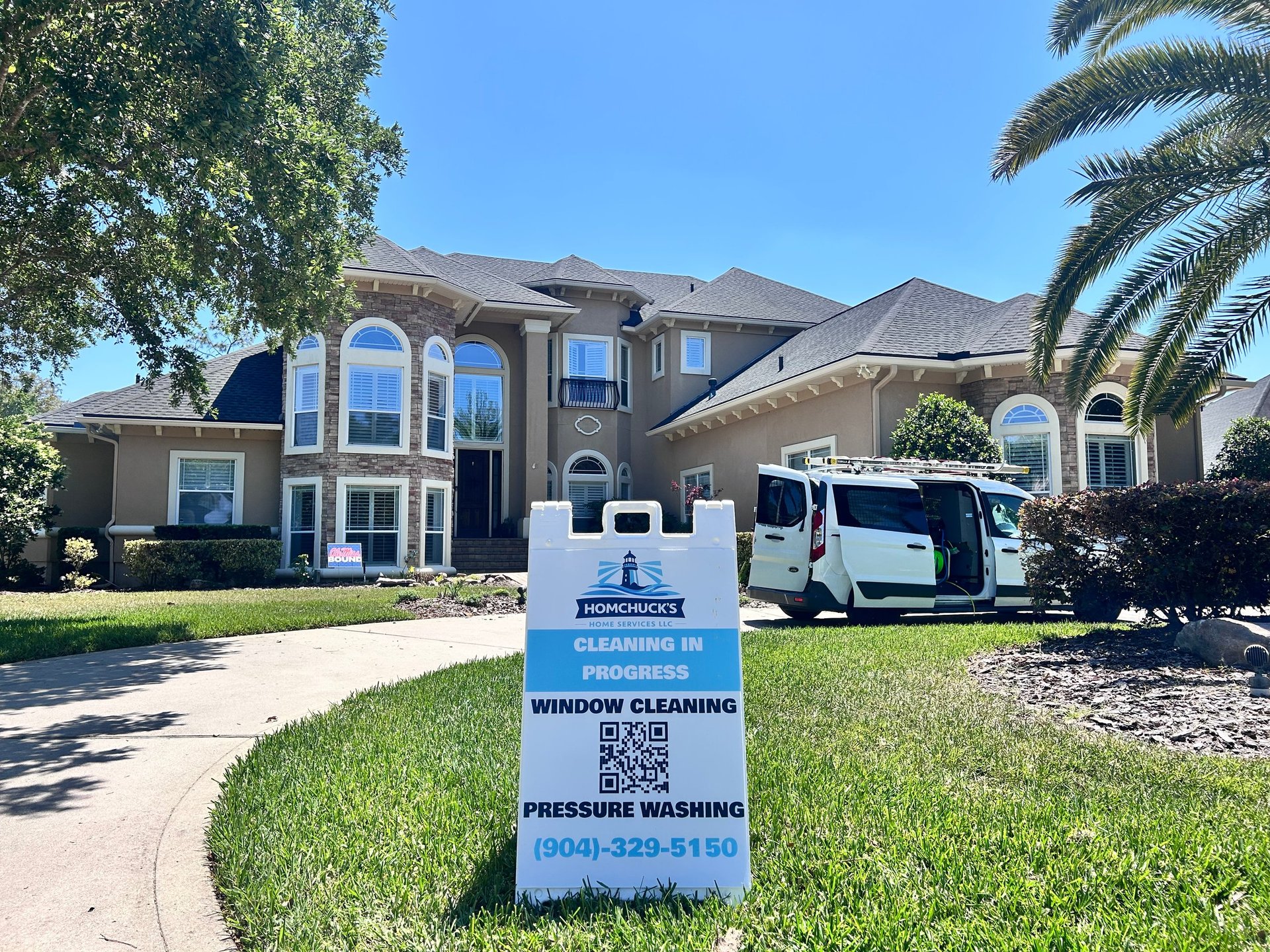 Professional cleaning service sign on lawn in front of large two-story stucco home with service van parked in driveway